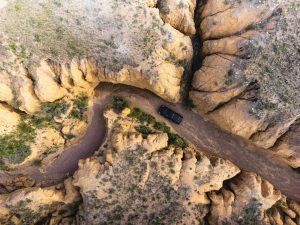 An aerial view of a car driving on a dirt road
