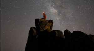 A person standing on top of a rock under a night sky