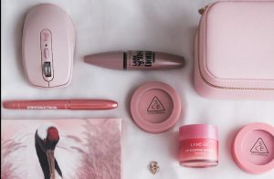 The contents of a pink purse laid out on a bed