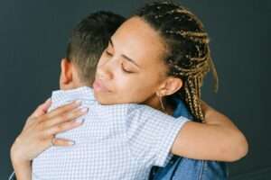 A loving mother holding and comforting her son in an emotional embrace indoors.