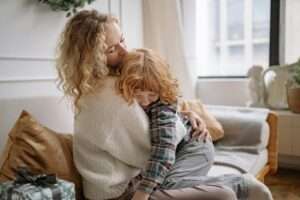 A tender moment between a mother and son sitting on a cozy living room couch.