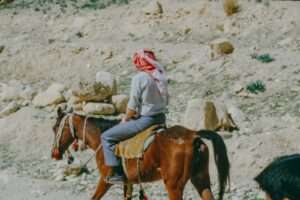 Man in traditional headscarf riding a horse