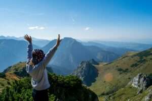 a person standing on top of a mountain with their arms in the air